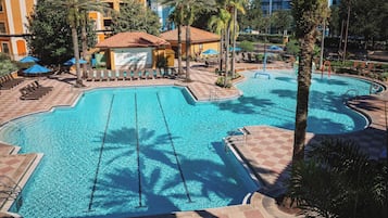 Un área de piscina hotelera con varias piscinas, sillas de descanso y palmeras.