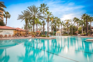 Zwembad omringd door palmbomen en ligbedden, met een gebouw waarop staat 'Florida's Resort' op de achtergrond.