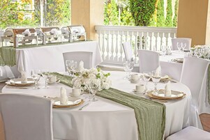 Een formele dineropstelling met witte tafelkleden, gouden onderborden en witte bloemstukken.