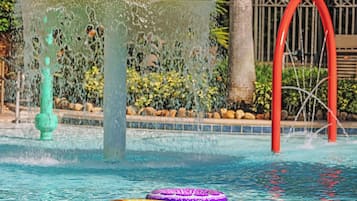 Una piscina con una fuente de agua, dos flotadores y una estructura en arco rojo.