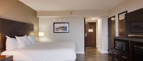 Quarto de hotel com uma cama, televisão, escrivaninha e espelho.