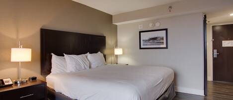 A hotel room with a large bed, bedside lamps, a nightstand, and a framed picture on the wall.