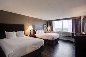 A hotel room with two beds, a desk, a chair, a lamp, and a large window with curtains. - The Hotel Hot Springs (Hot Springs)