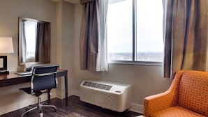 Habitación de hotel con escritorio, silla, aire acondicionado y vista por la ventana.