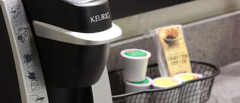 A Keurig coffee machine with a coffee pod basket containing various pods.