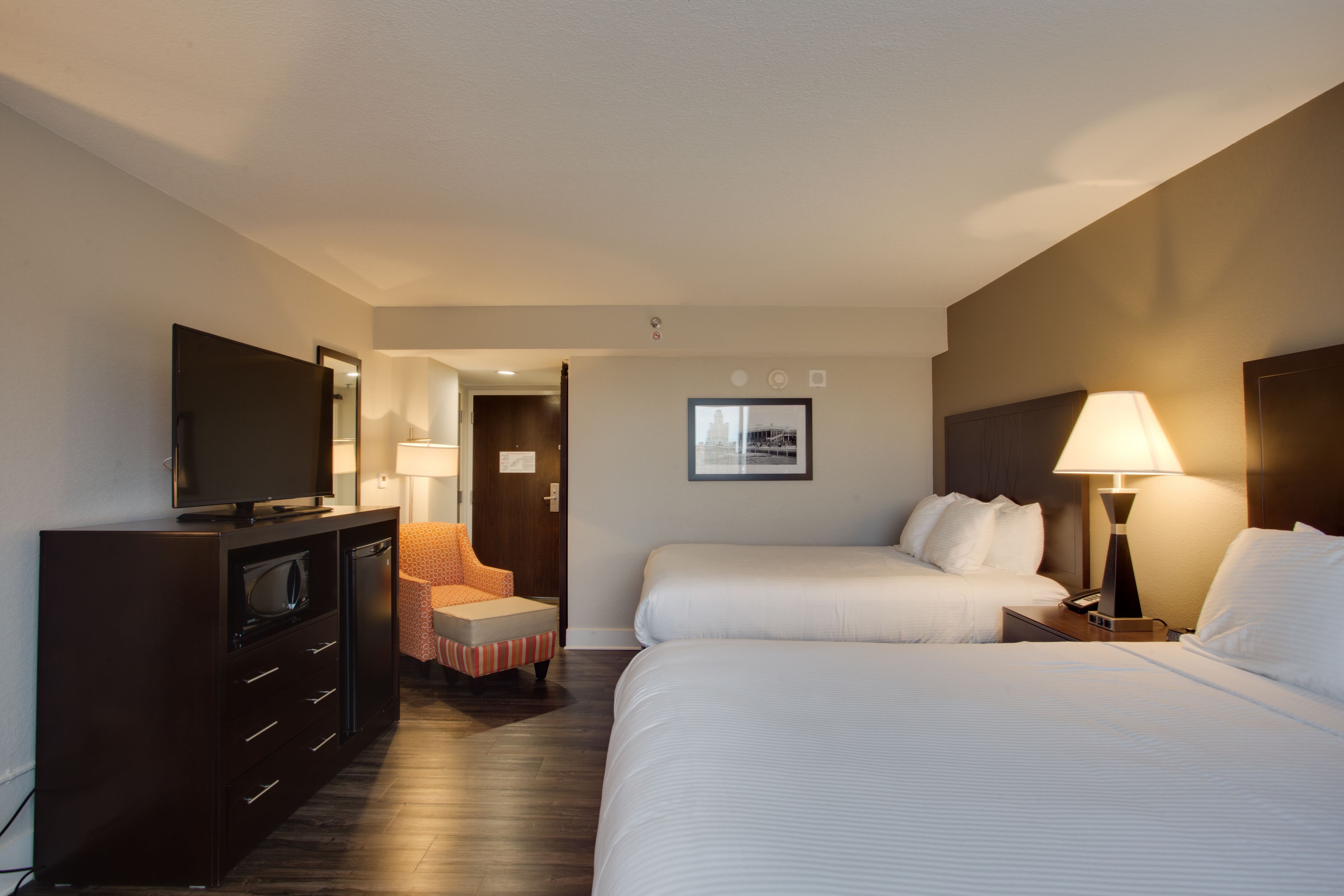 A hotel room with two beds, a TV, a desk, and a chair.