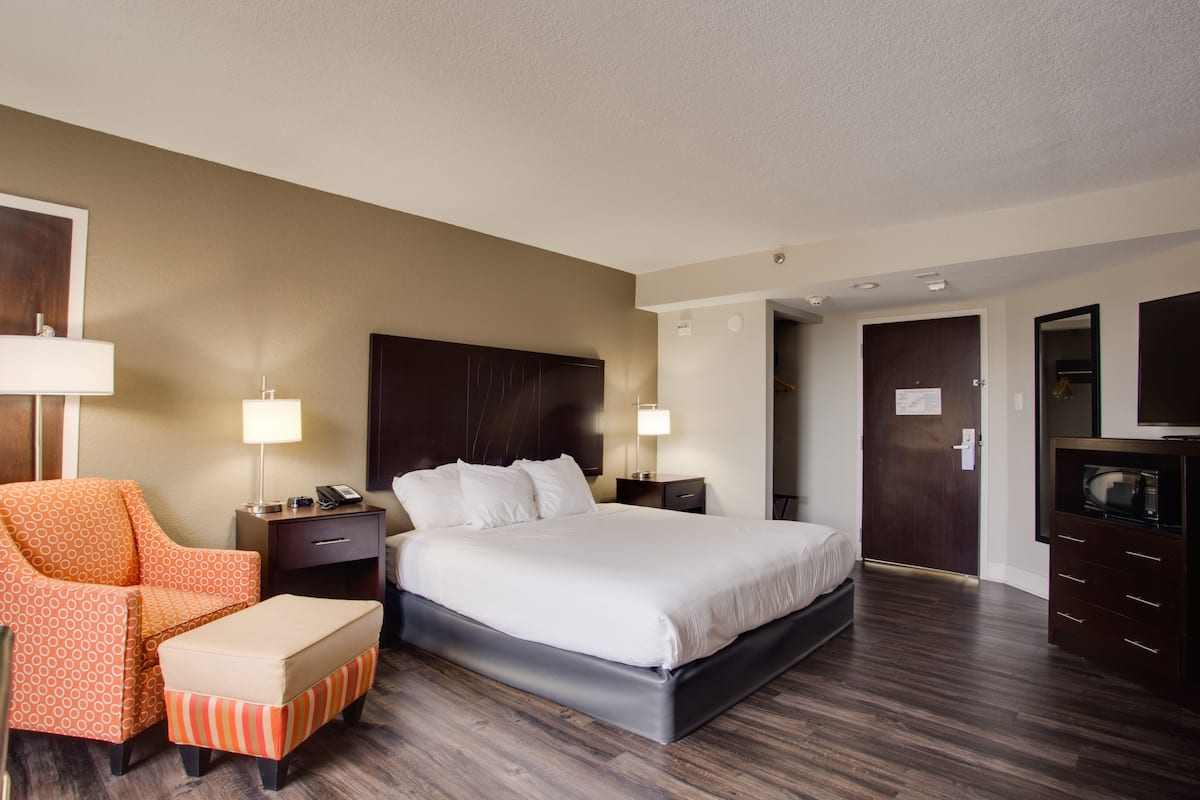 Una habitación de hotel con una cama grande, una silla, un escritorio y un aparador.