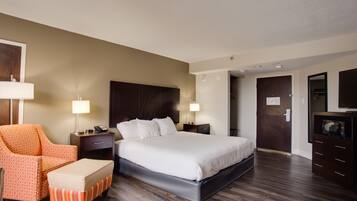 Une chambre d’hôtel avec un grand lit, une chaise, un bureau et une commode.