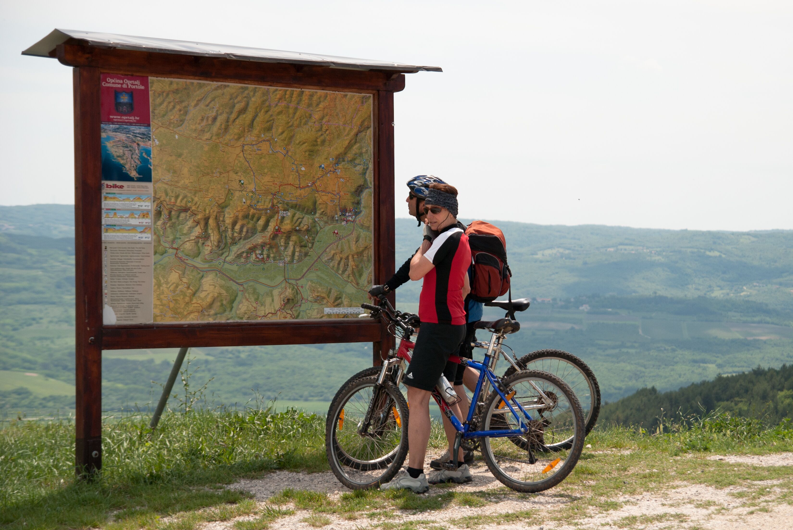 Vista de la montaña con un poste de madera que muestra un mapa e información.