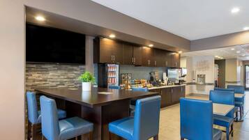 A modern kitchen with dark wood cabinets, a stone backsplash, and blue bar stools.