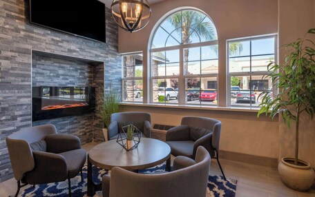 A modern lounge area with a fireplace, comfortable seating, and large windows offering a view of the street.