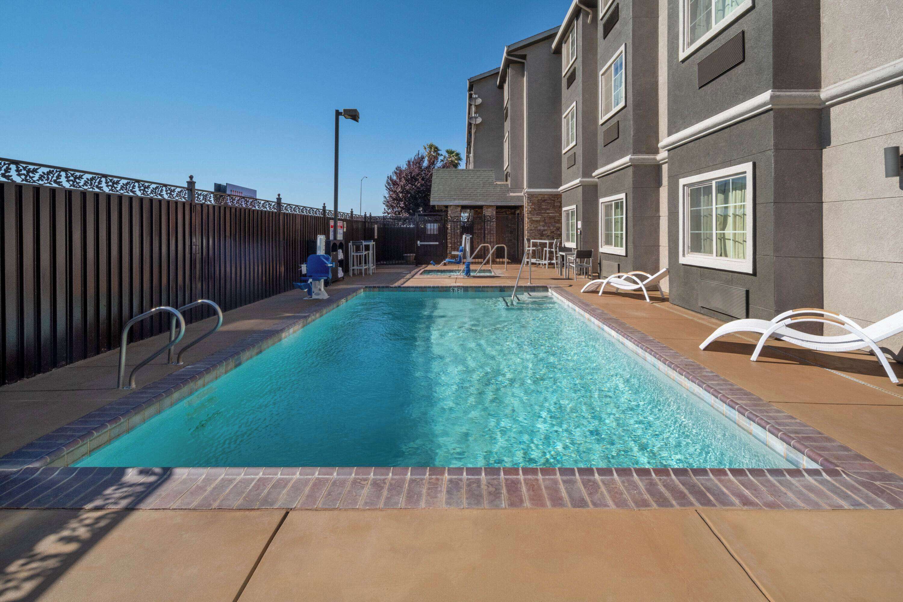 A rectangular swimming pool with a metal ladder and a wooden deck.