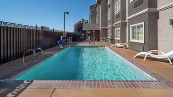 A rectangular swimming pool with a metal ladder and a wooden deck.