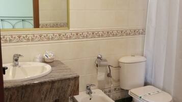 A bathroom with a sink, bidet, toilet, and a mirror.