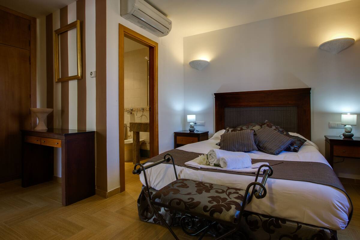 Una habitación de hotel con cama, mesitas de noche, escritorio y una silla.