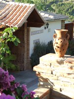 A rustic building with a tiled roof, a sign reading "RECEPTION," and a large clay pot in the foreground.