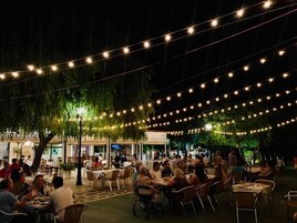 An outdoor dining area with string lights and tables under a covered section.