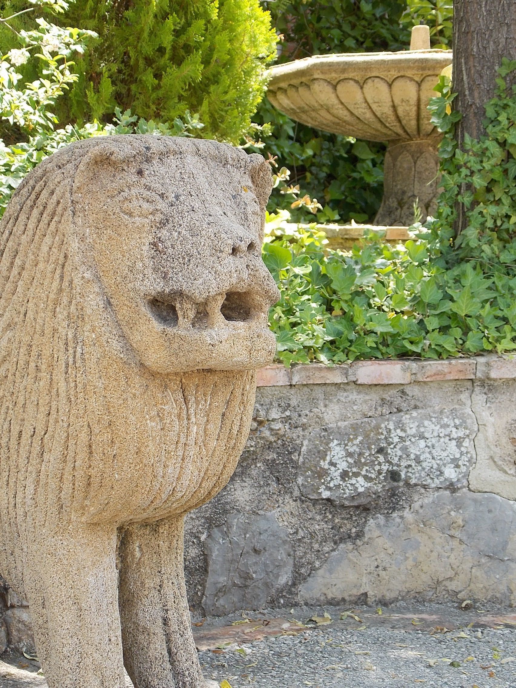 A stone lion statue in a garden setting.