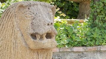 A stone lion statue in a garden setting.