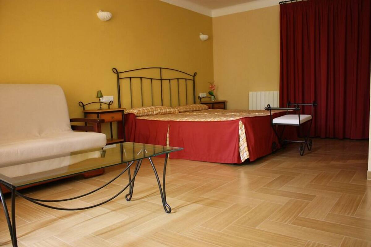 Una habitación con una cama, un sofá, una mesa de vidrio y una silla.