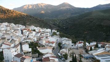 Un pueblo con edificios blancos, una calle principal y montañas al fondo.