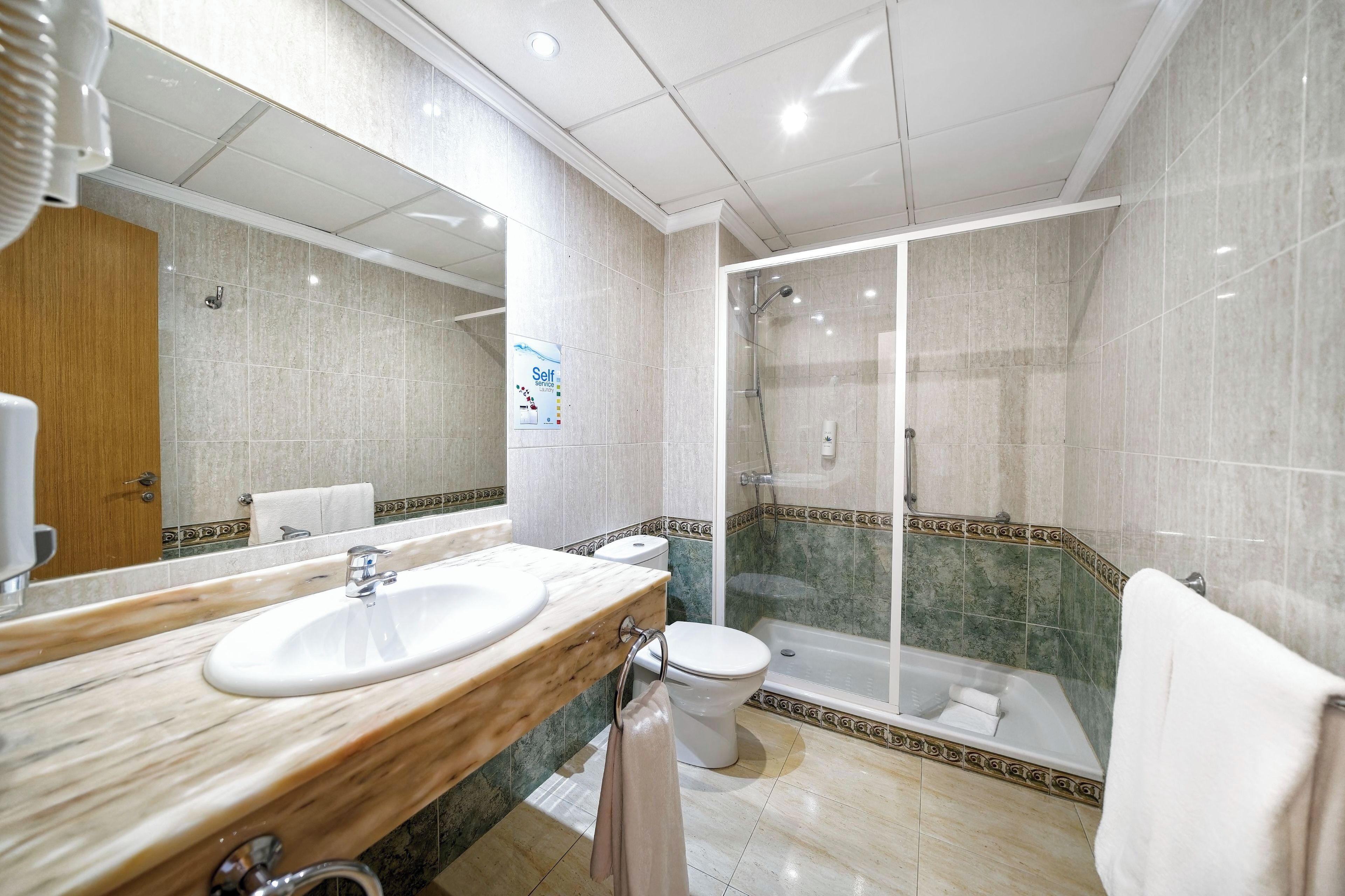 A modern bathroom with a marble sink, toilet, and a glass-enclosed shower area.