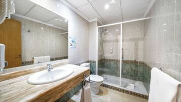 A modern bathroom with a marble sink, toilet, and a glass-enclosed shower area.