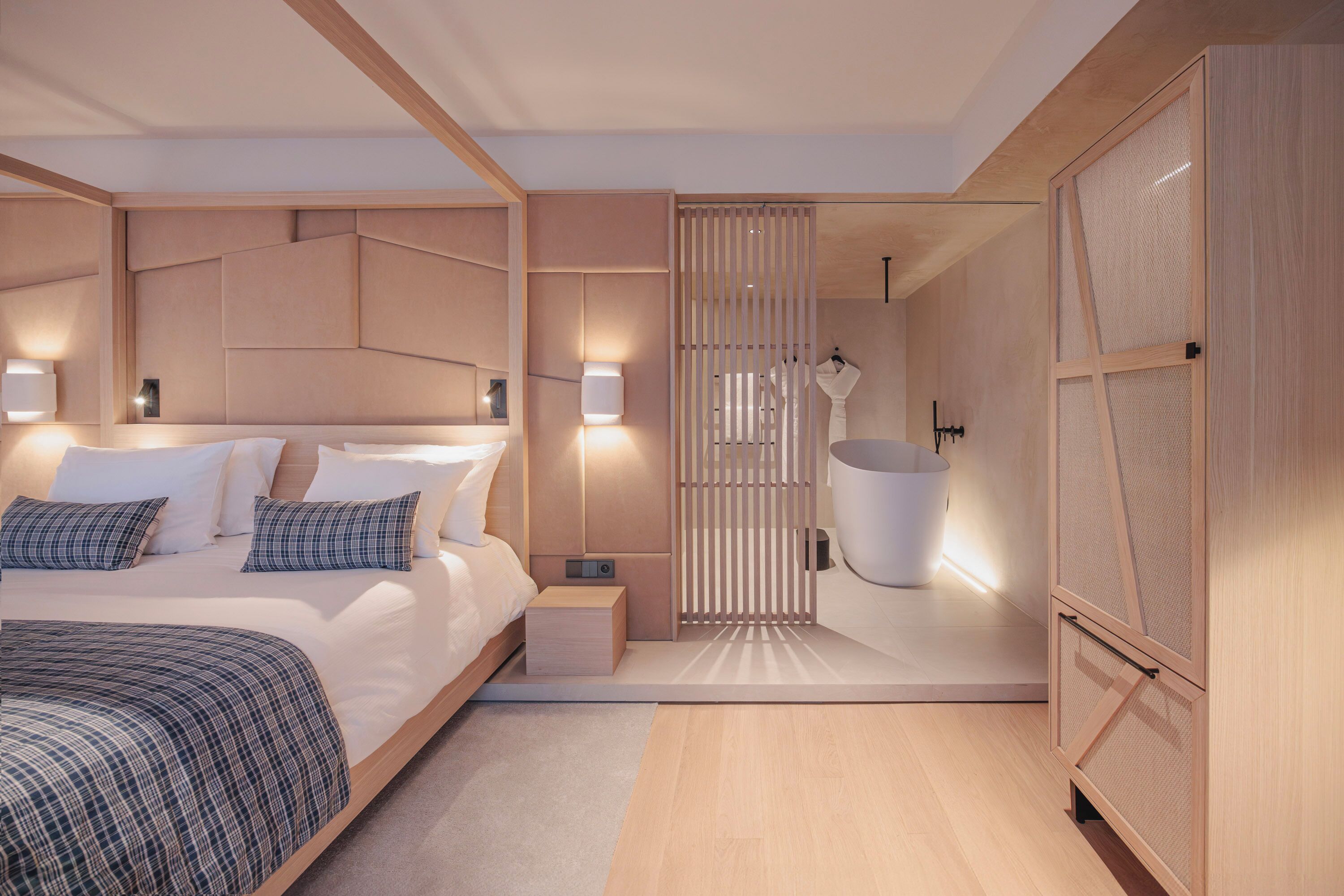 Une chambre moderne avec un grand lit, des tables de chevet, une commode, une armoire intégrée et une salle de bain avec une baignoire.