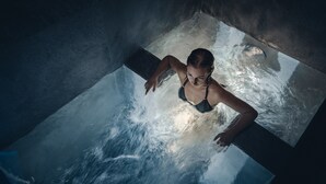 A person in a bathtub with water flowing around them.