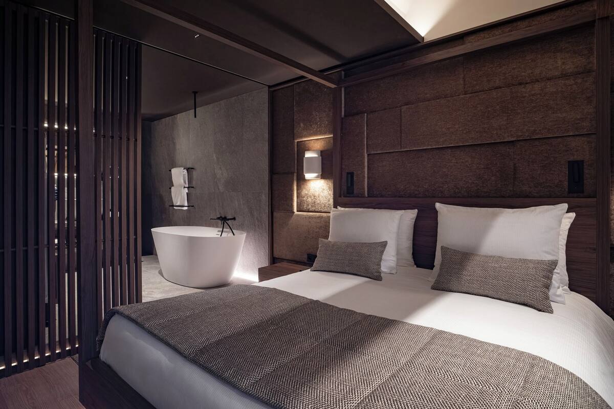 Une chambre moderne avec un grand lit, une baignoire et une cloison en bois.