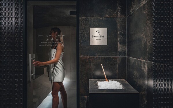 A person in a robe entering a steam bath area with a sign indicating it is a scrub spa. - YONA ex Le Parc Hôtel (Obernai)