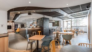 Un café moderno con una barra curva, mesas de madera y sillas coloridas.