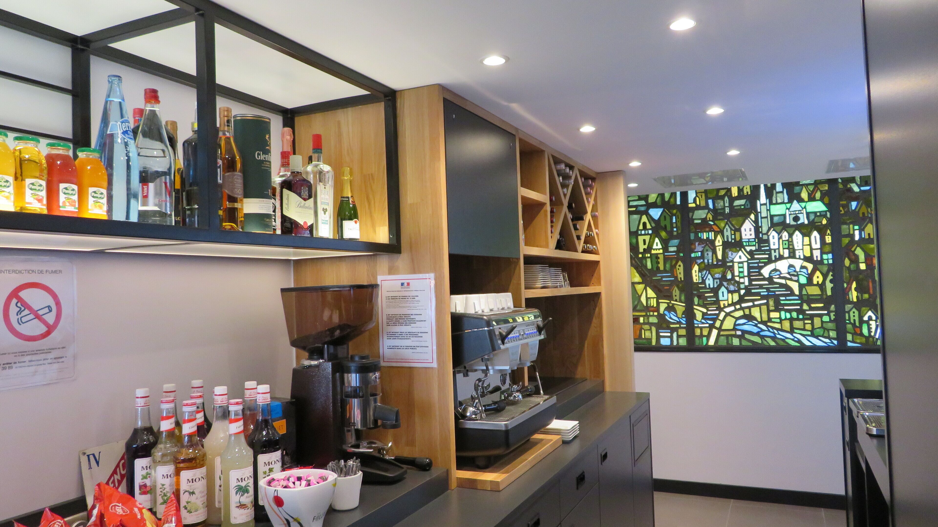 A bar area with shelves of liquor bottles, a coffee machine, and a stained glass window.