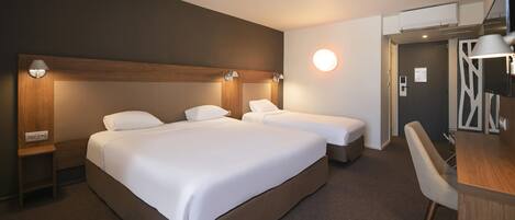 A hotel room with two beds, a desk, and a chair.