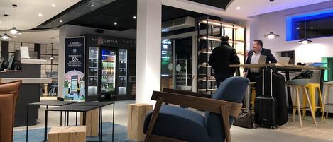 Un moderno vestíbulo de hotel con zona de estar, minibar y bar.