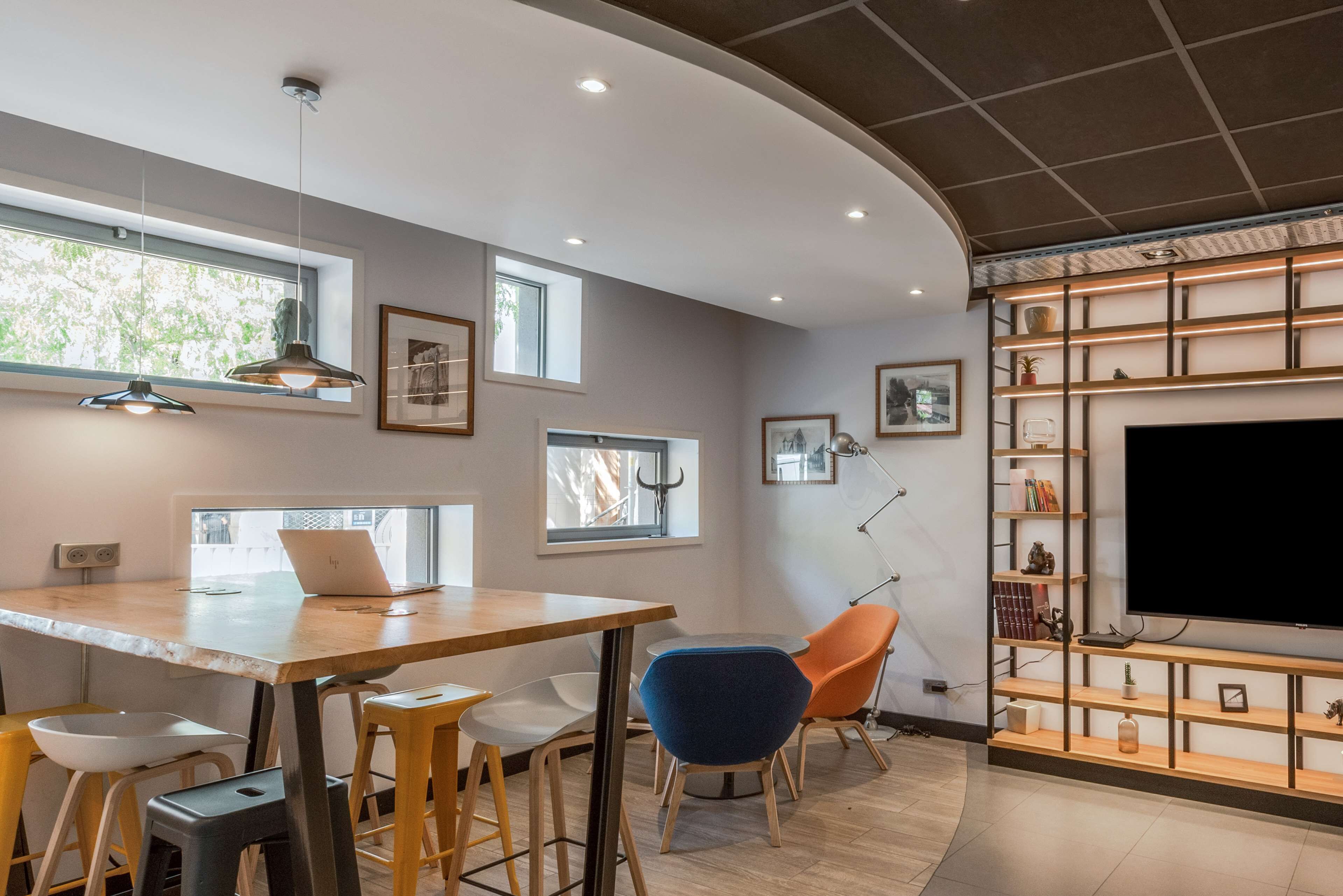 Una cocina moderna con una mesa de madera, taburetes de bar y un mueble empotrado para la televisión.