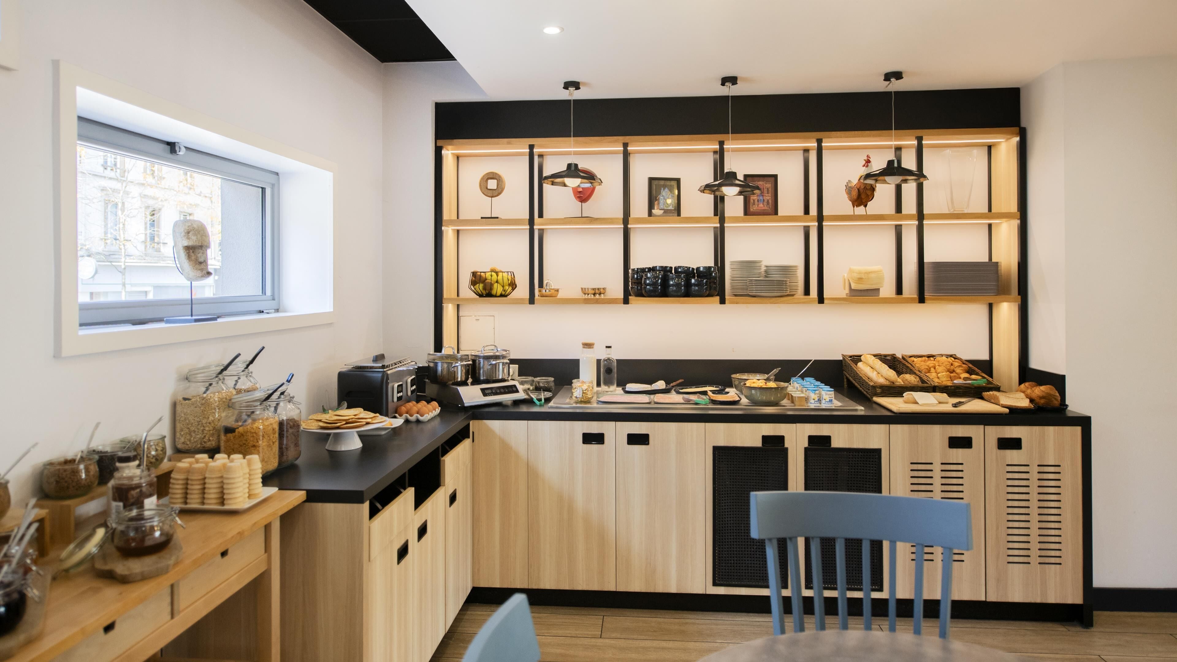 A modern kitchen with wooden cabinets, a black countertop, and a variety of breakfast items.
