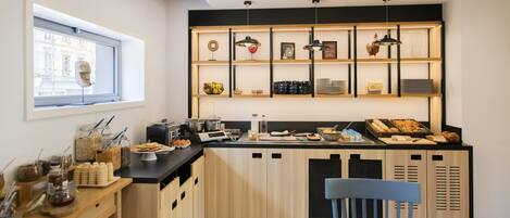 Una cocina moderna con armarios de madera, encimera negra y diversos productos para el desayuno.