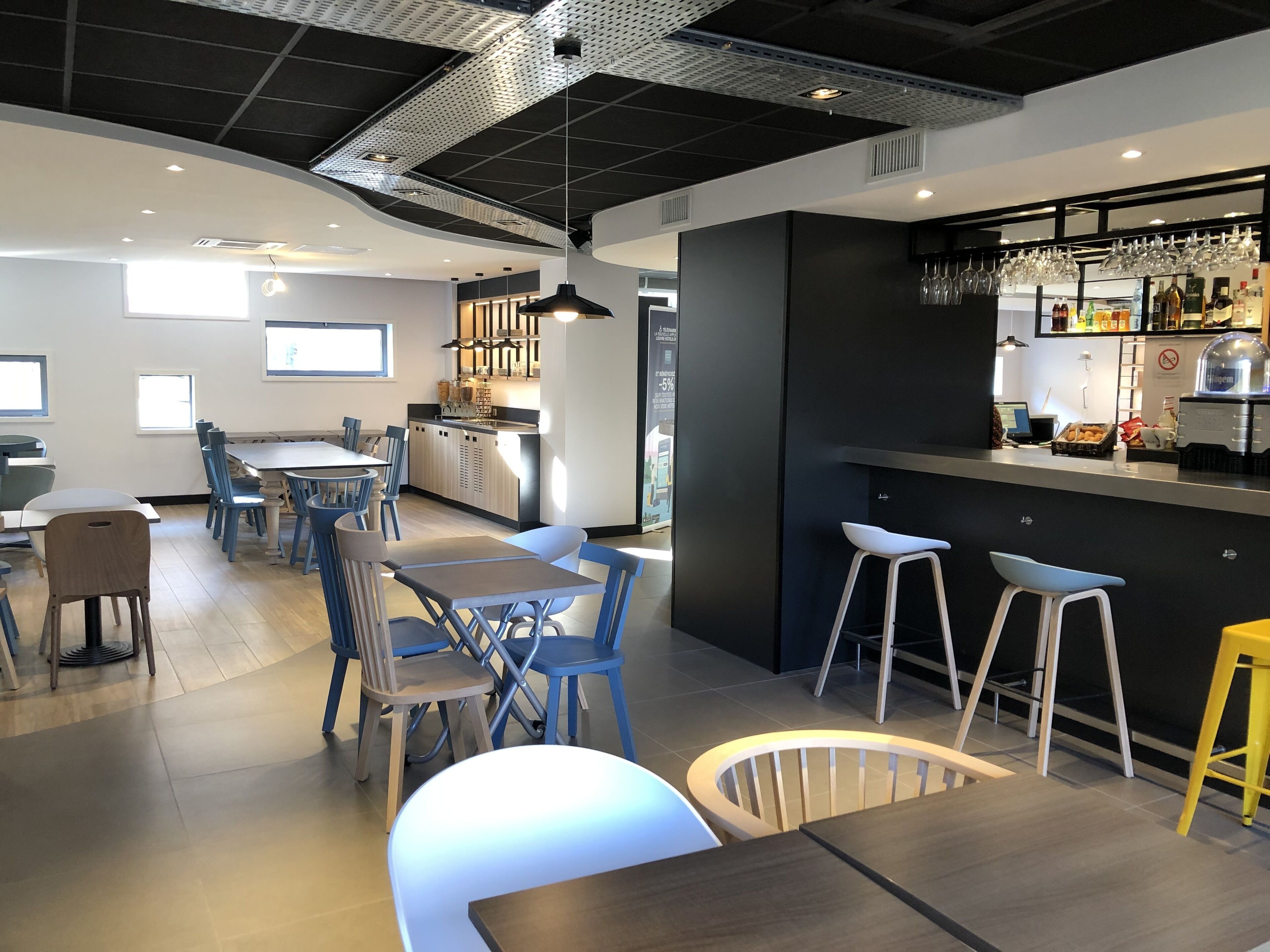 A modern restaurant with a bar area, dining tables, and chairs.