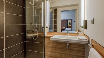 Ein modernes Badezimmer mit Duschkabine aus Glas, einem Holzbadschränken mit Waschbecken und einem Spiegel.