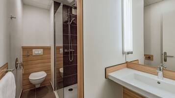 Une salle de bain moderne avec une douche à parois de verre, des toilettes blanches et un meuble-lavabo en bois avec un évier.