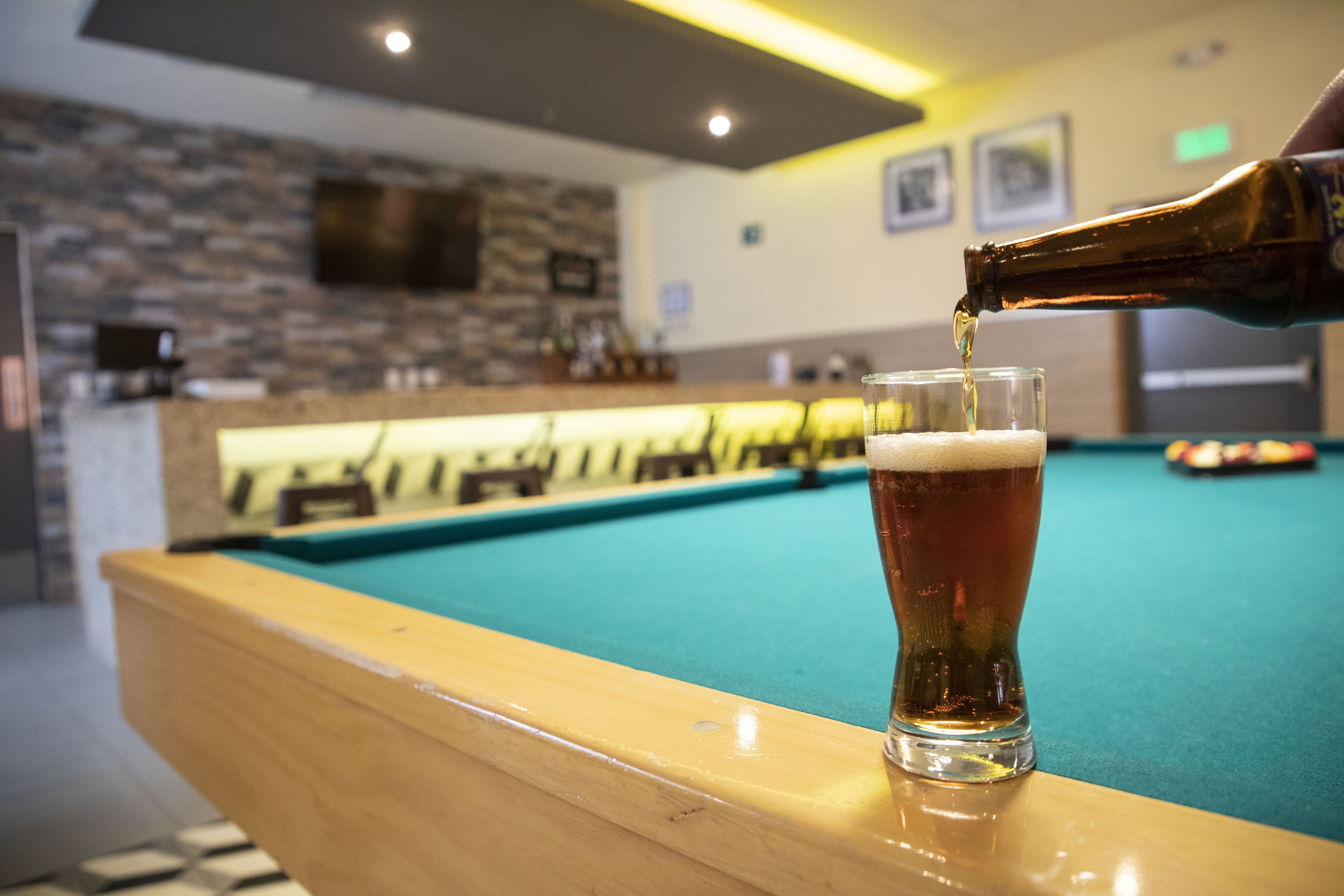 Een bar met een pooltafel en een biertje dat wordt in geschonken.