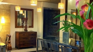 A modern dining area with a glass table and chairs, a wooden cabinet, and a large mirror on the wall. - Rusticae Las Casas del Cónsul (Úbeda)