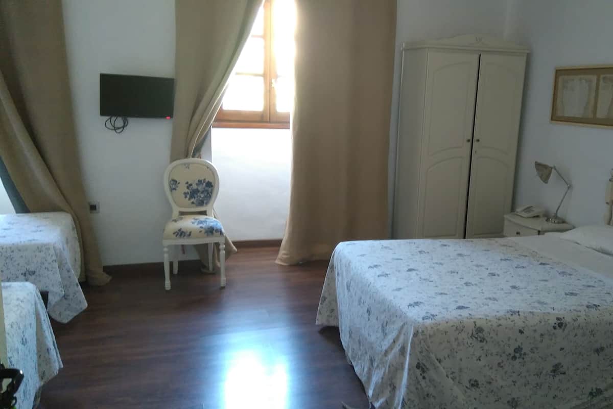 A bedroom with a bed, a chair, a wardrobe, and a desk with a lamp.