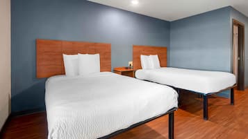Habitación de hotel con dos camas y cabeceros de madera, y una pared azul.