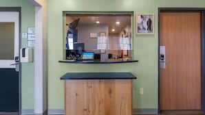 A reception desk with a computer, a coat check, and a wooden cabinet. - Extended Stay America Select Suites - Lubbock - West (Lubbock)
