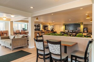 A modern interior with a bar area, seating, and a kitchen in the background.