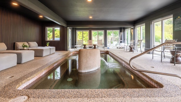 A spa area with a hot tub, seating, and large windows. - The Meadowmere Resort (Ogunquit)