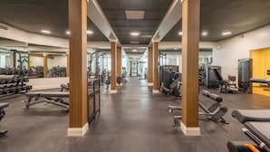 A gym with various exercise equipment, wooden pillars, and a mirrored wall. - The Meadowmere Resort (Ogunquit)