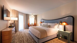 A hotel room with a bed, bedside tables, a dresser, a mirror, and a patterned carpet. - The Meadowmere Resort (Ogunquit)